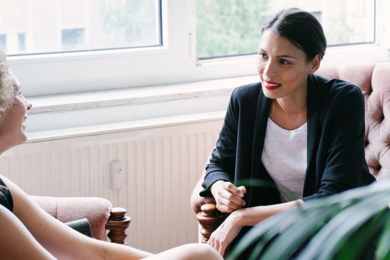 Office scene, two businesswomen. Informal coaching session on the sofa.