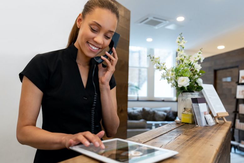 Woman working at a spa talking on the phone and making a booking